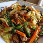 Pork and cabbage stir-fry with carrots and scallions.